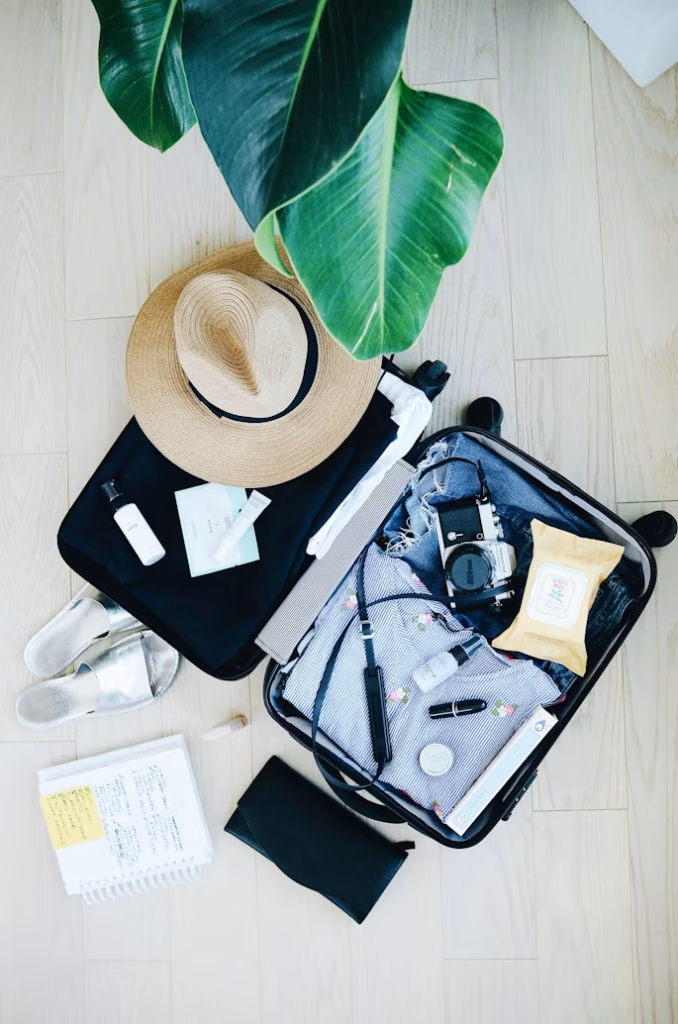 Open suitcase with summer travel essentials and hat